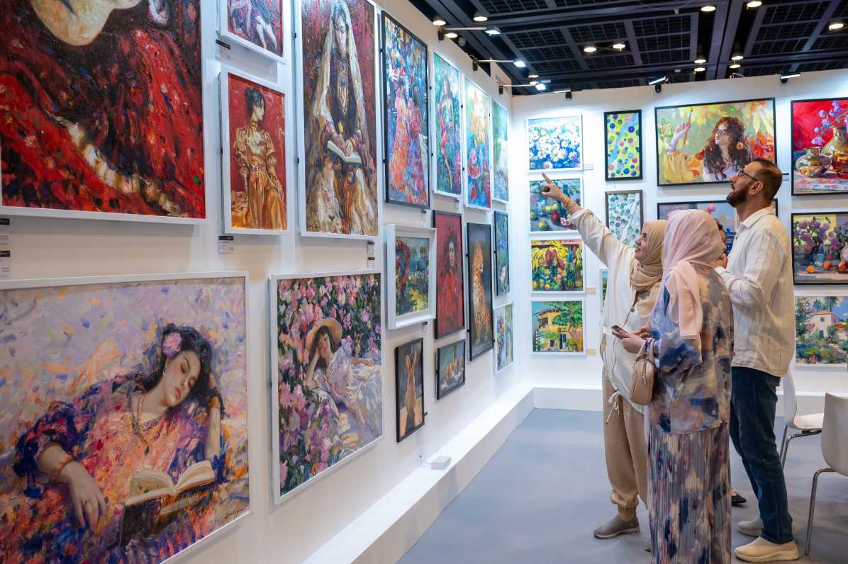 Visitors exploring paintings at a gallery booth during World Art Dubai art fair